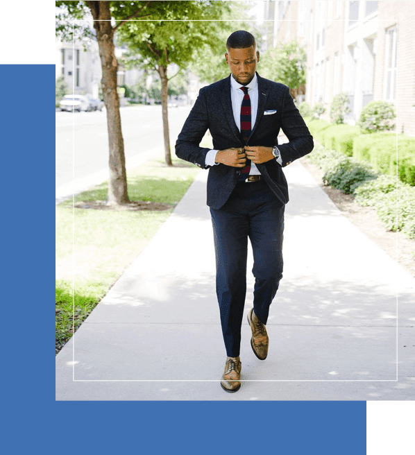 A man in suit and tie walking down the sidewalk.